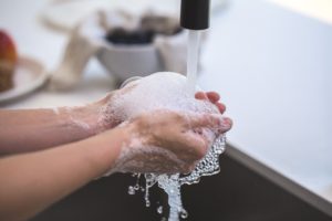 person washing hands at a kitchen sink