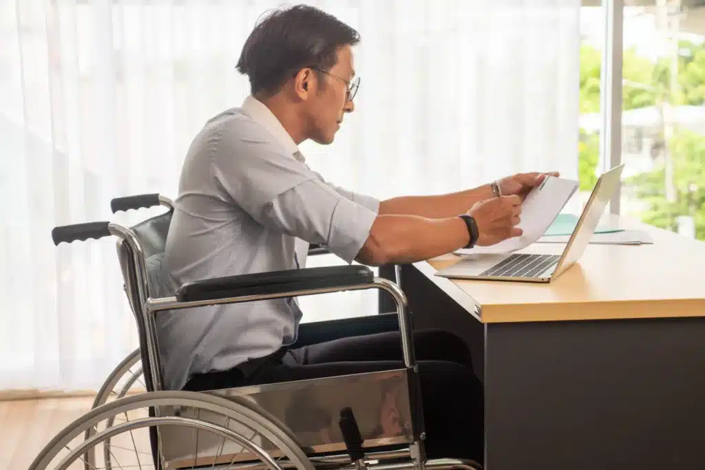 businessman sitting on wheelchair and checking documents at the office.