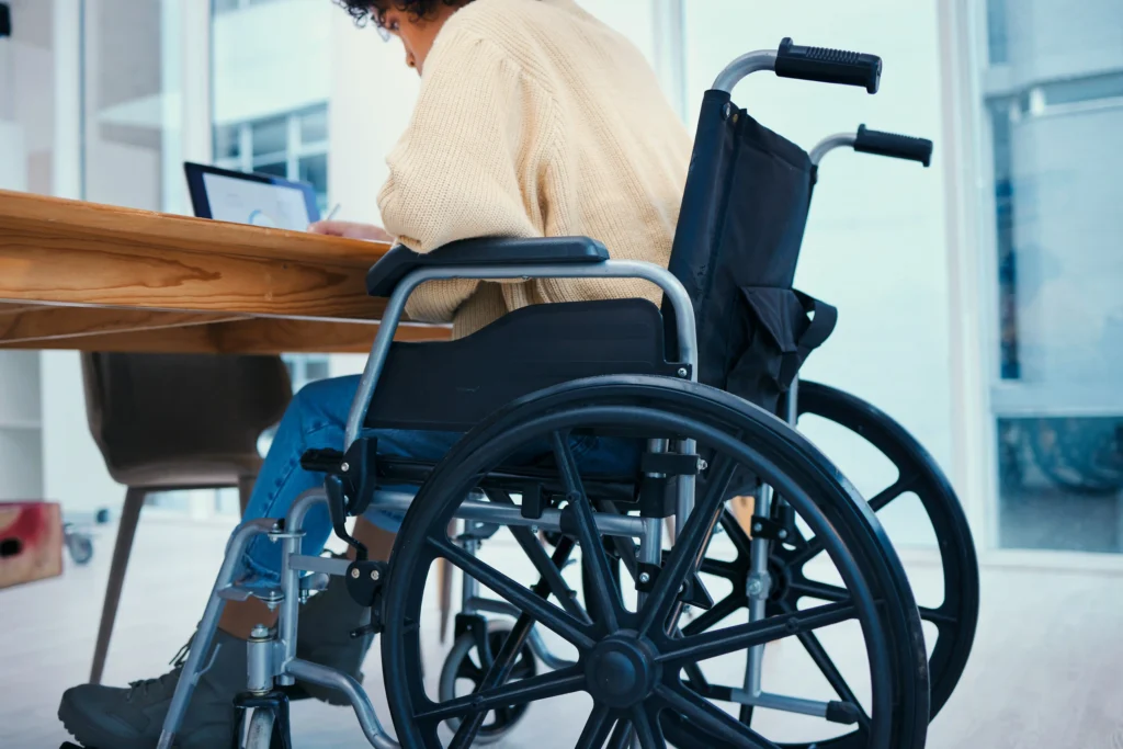desk and worker in wheelchair in office, working.