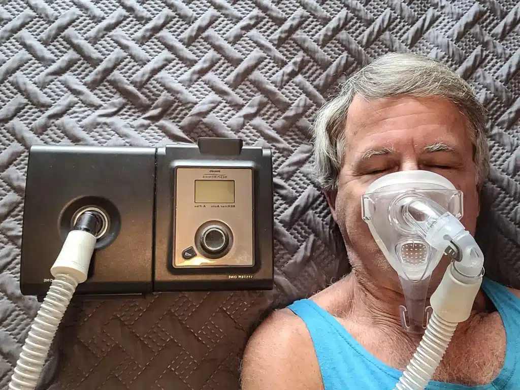 CPAP machine in use by a sleeping older man in bed