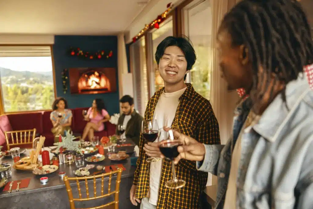 Happy friends enjoying in conversation and drinking wine during festive dinner at home party