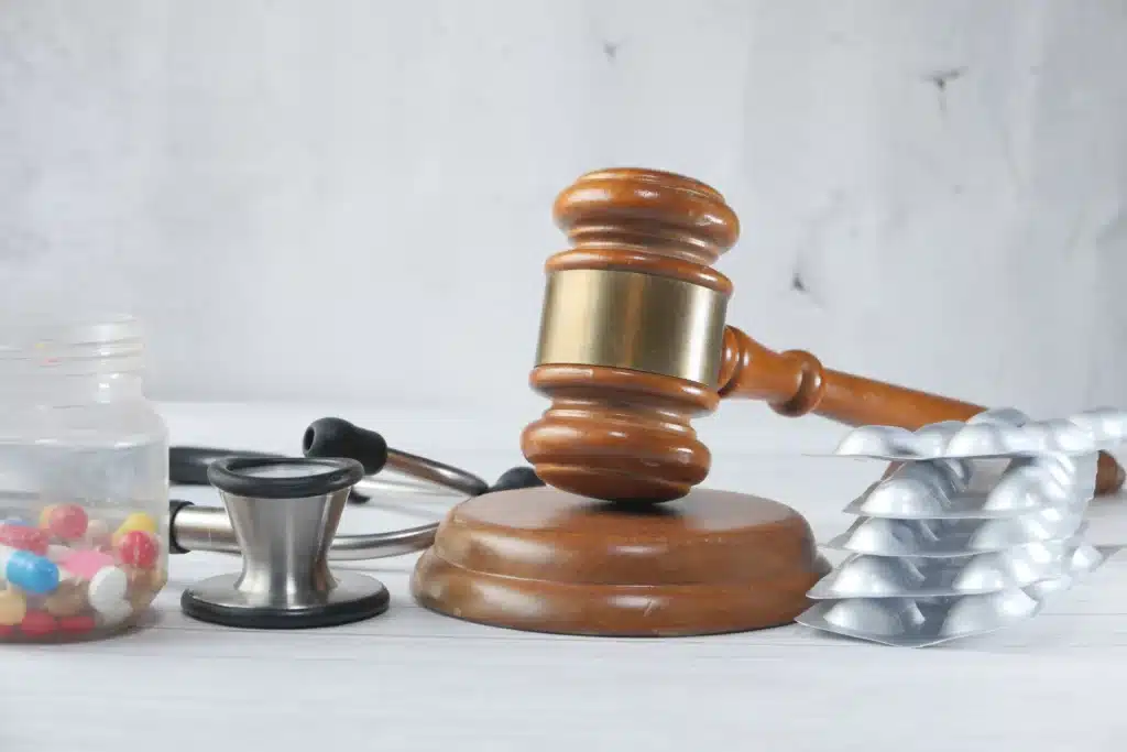 Judge gavel and stethoscope with pills on table