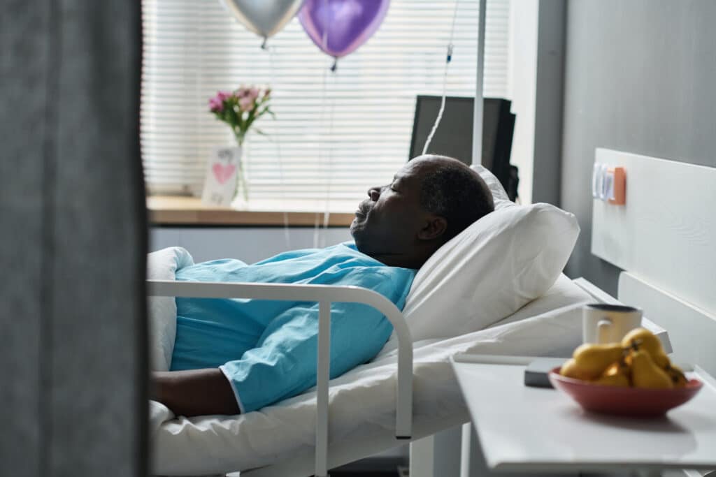 man sleeping in hospital ward bed