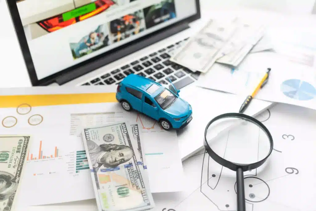 Money on table with laptop and toy car