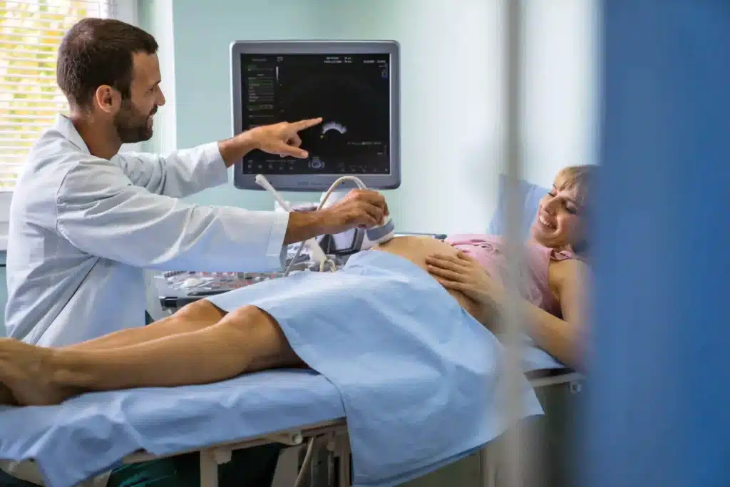 Obstetrician examining pregnant woman belly by ultrasonic scan in hospital