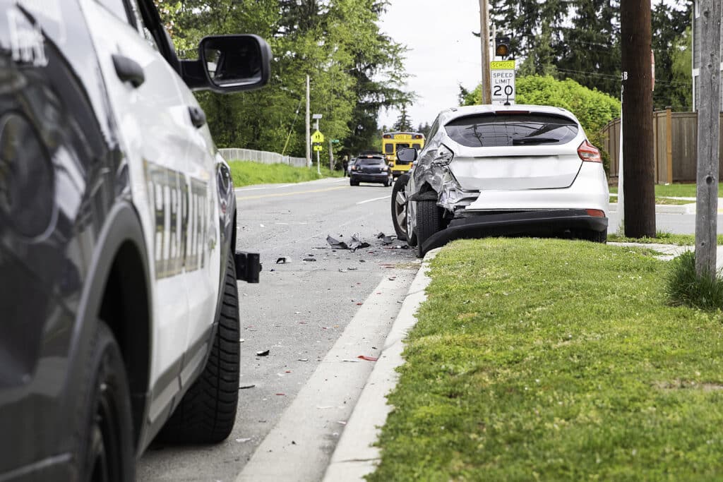 police car driving towards a damaged car on the side of road