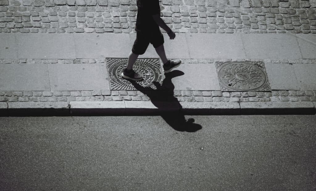silhoutte of person walking on sidewalk