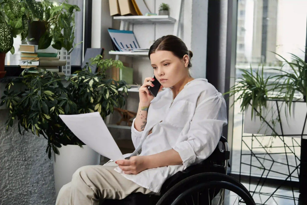 Young woman in a wheelchair holding paperwork on the phone