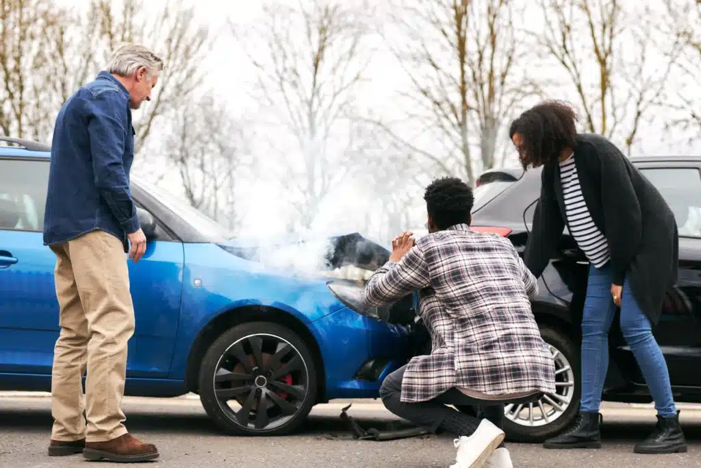 Man taking pictures of a car accident with two other people present