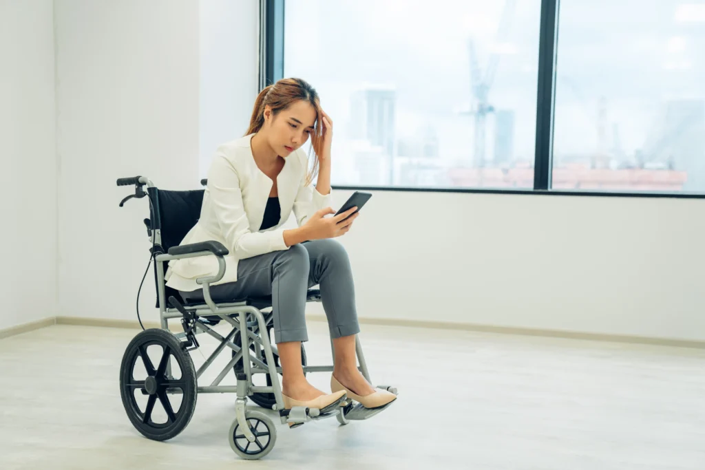 Young disabled business woman in wheelchair using mobile phone at office.